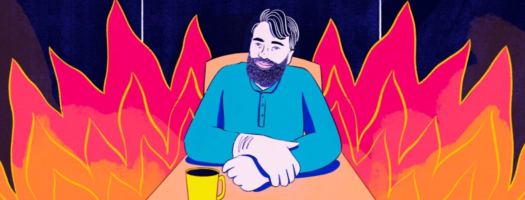 A man smiling and sitting at a table with a cup of coffee surrounded by flames