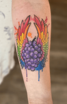 Photo of a tattoo of purple grapes with wings